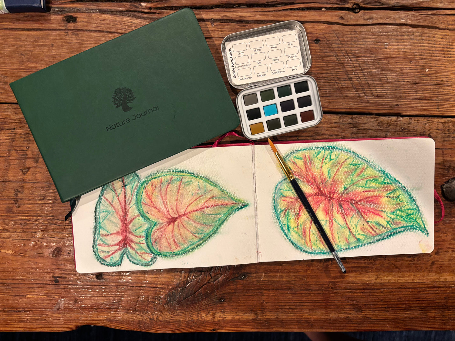 Watercolor leaf studies in a Forest Green nature journal